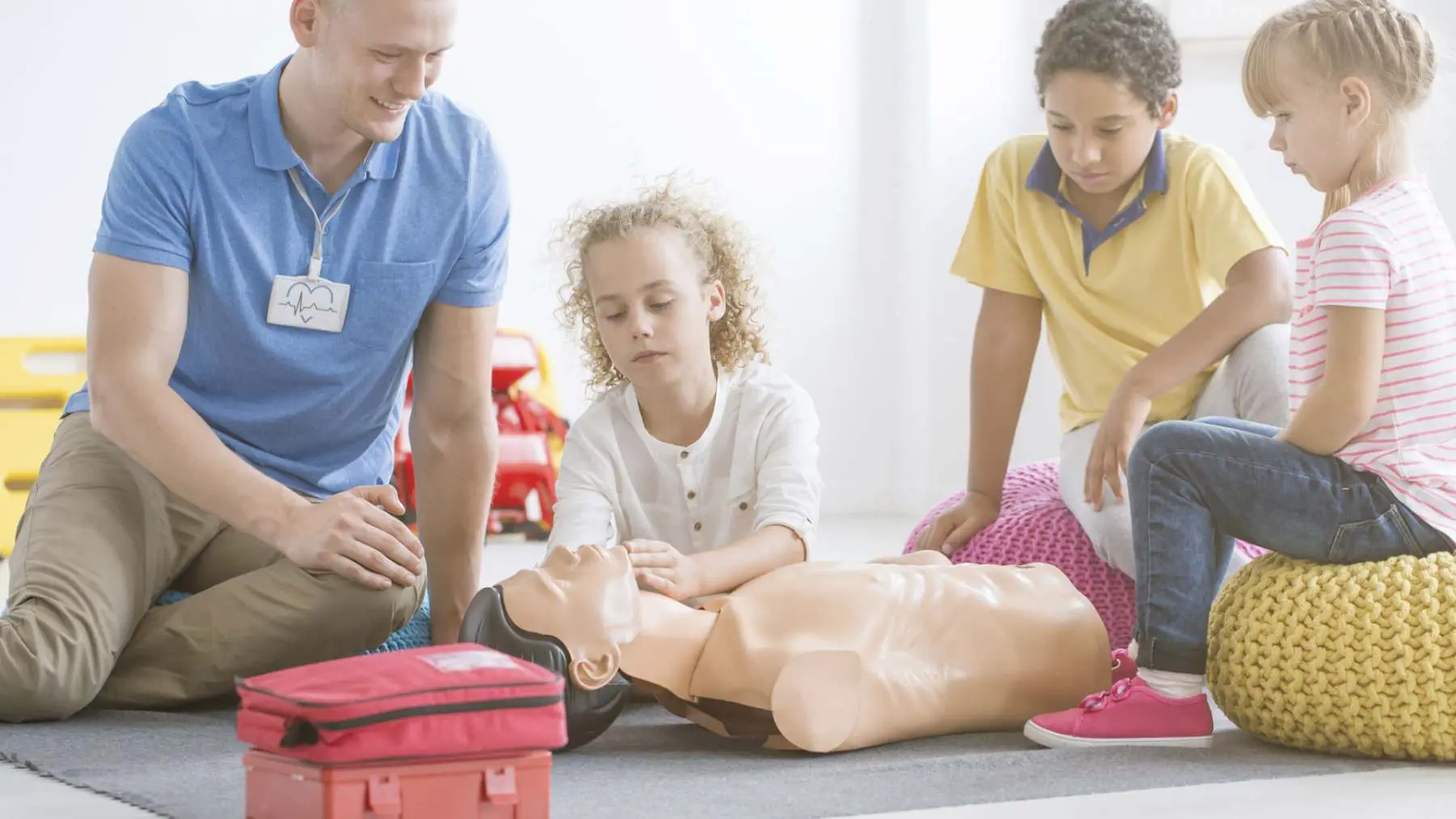 Child practising resuscitation on a manikin during first aid in schools training Assured First Aid Salisbury
