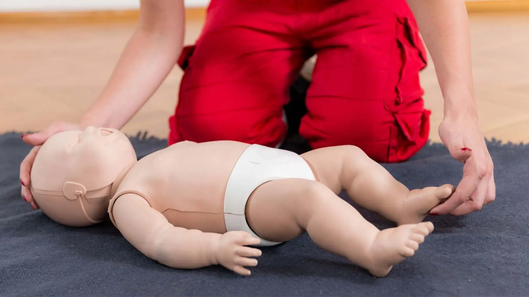 Baby CPR practice on an infant manikin on a first aid course for parents Assured First Aid Salisbury