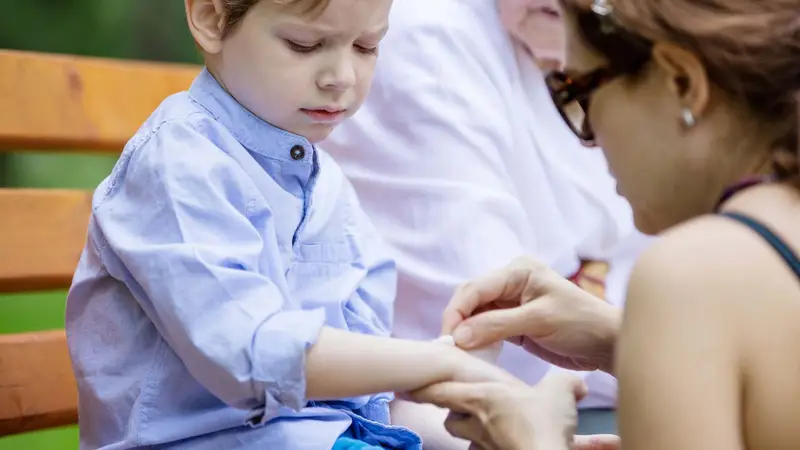Parent applying a plaster to a child during first aid for parents Assured First Aid Wiltshire
